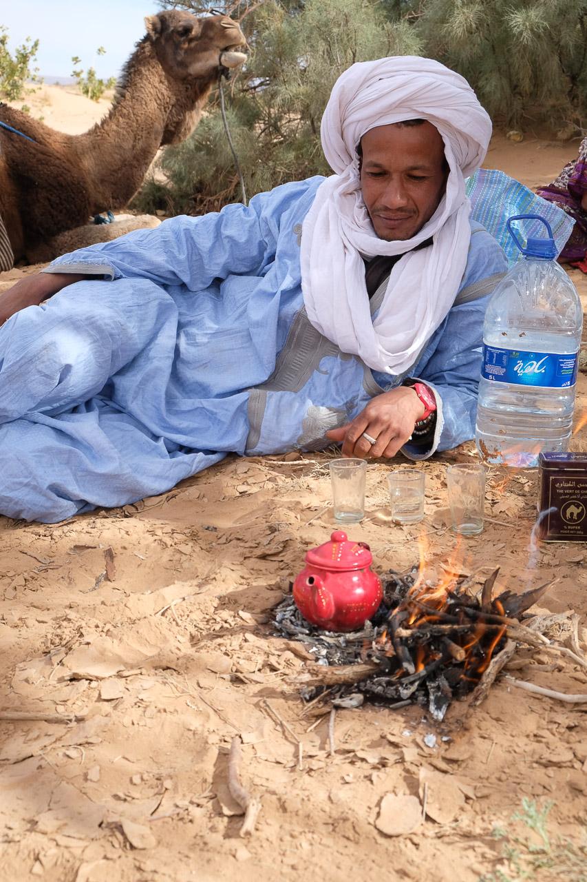 Mouloud Tazint preparing traditional tea by a campfire in the Sahara Desert
