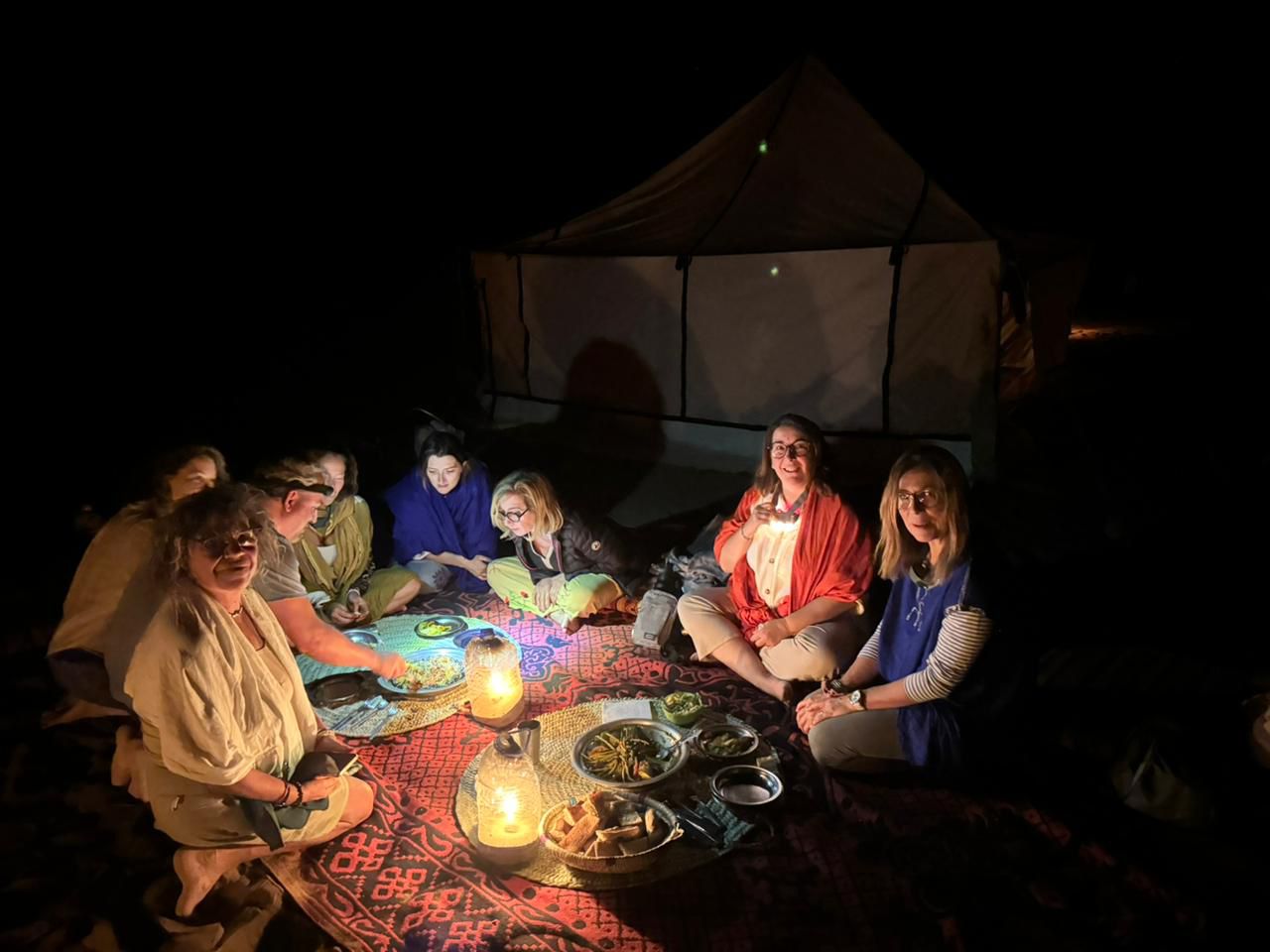 Group of tourists sharing dinner by candlelight in a desert tent